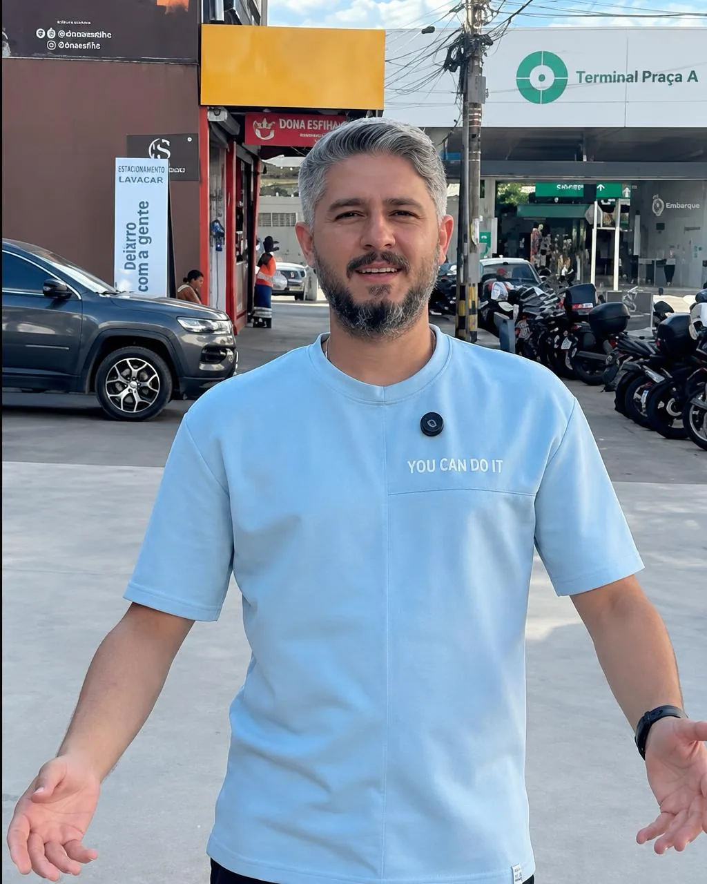 Responsável pela Bazel Variedades, de camisa azul-céu, em frente à loja